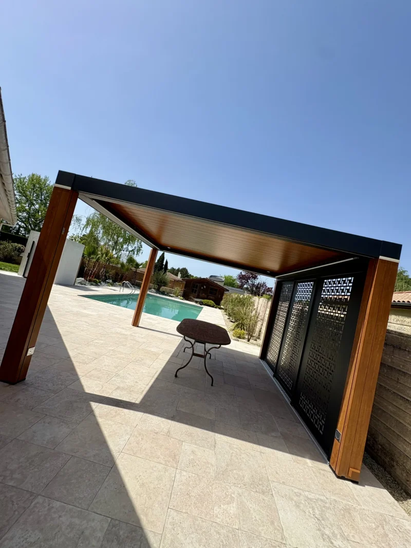 Pergola CEBEL Carat installée en bord de piscine sur une terrasse en travertin