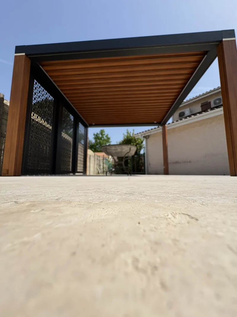 Détail des lames orientables teinte chêne doré de la pergola, vue en contre-plongée