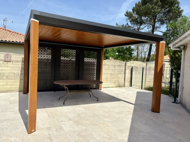 Pergola bioclimatique posée sur îlot à Saint-Jean-d'Illac, lames et poteaux teinte chêne doré