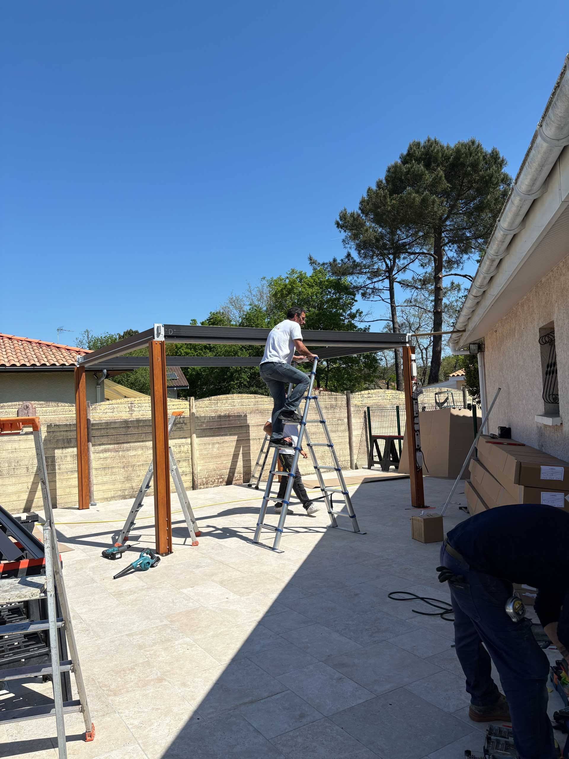 Pose d'une pergola aluminium à montants ton bois par l'équipe AM Atlantique sur une terrasse en Gironde