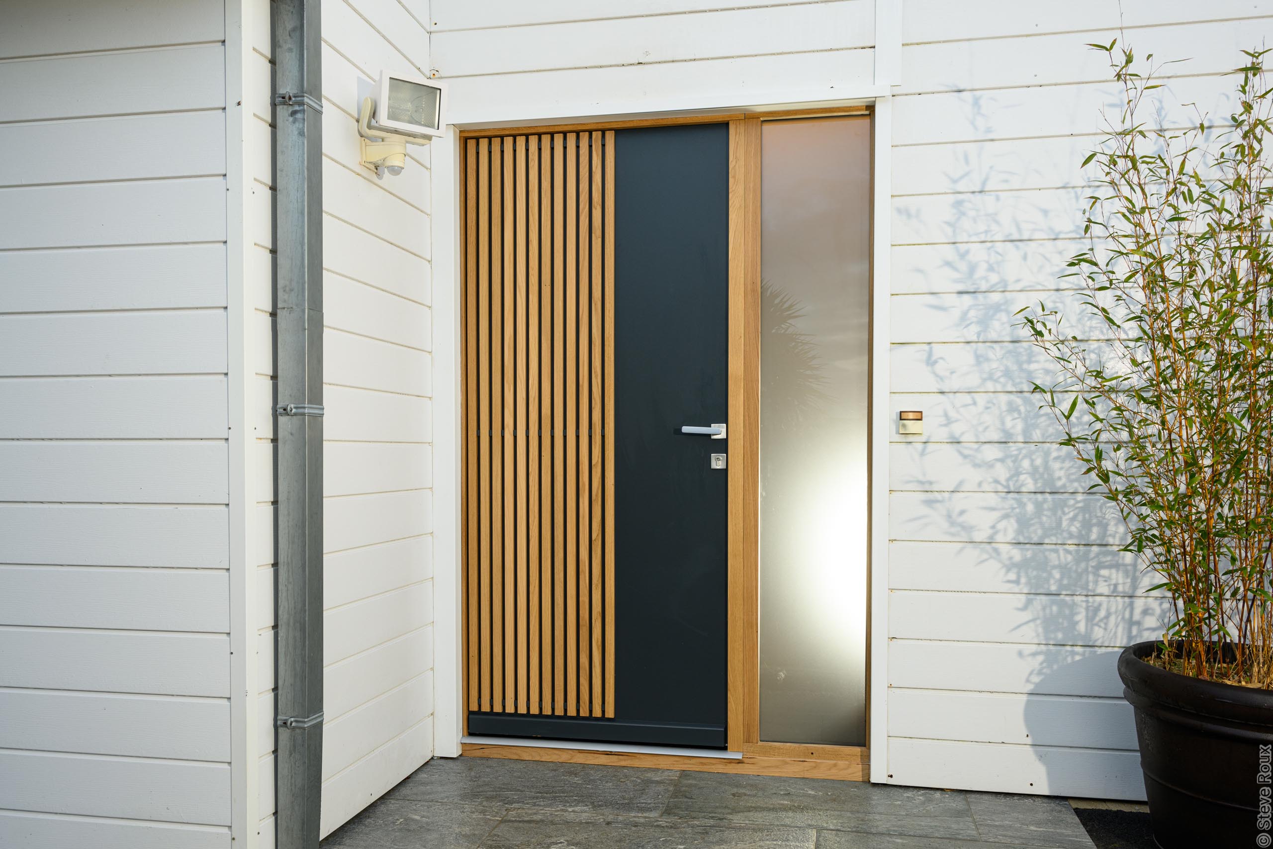 Détail d'une porte d'entrée aluminium à lames bois et panneau anthracite avec imposte vitrée, installée par AM Atlantique