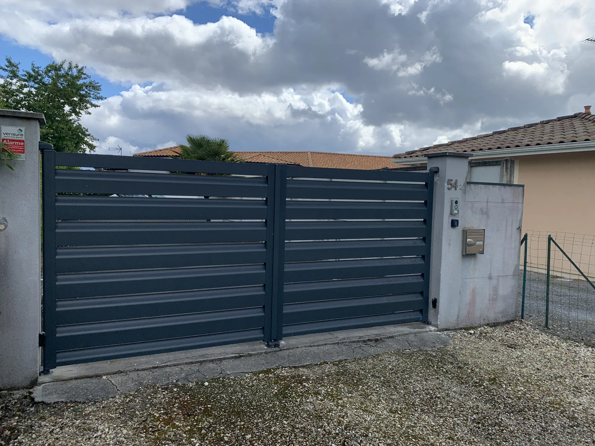 Portail battant aluminium fermé devant une haie de bambous, entrée d'une maison à Pessac