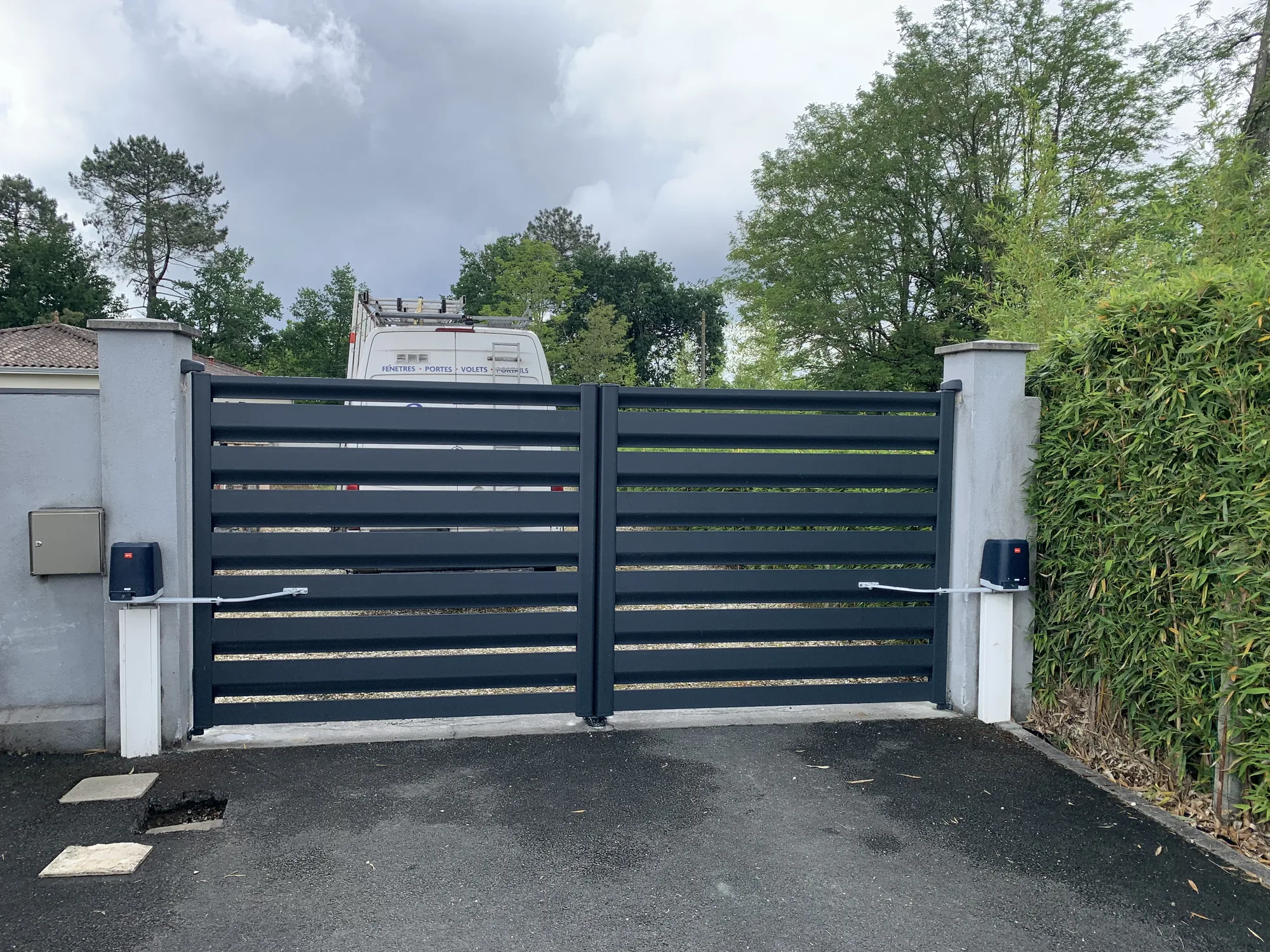 Portail battant motorisé vu depuis l'intérieur de la propriété, allée goudronnée à Pessac