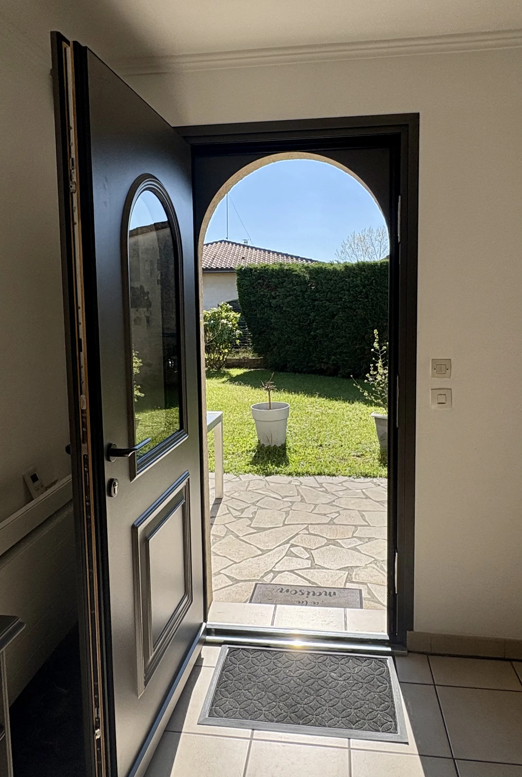 Vue depuis l'intérieur à travers la porte de service ouverte sur la terrasse et le jardin