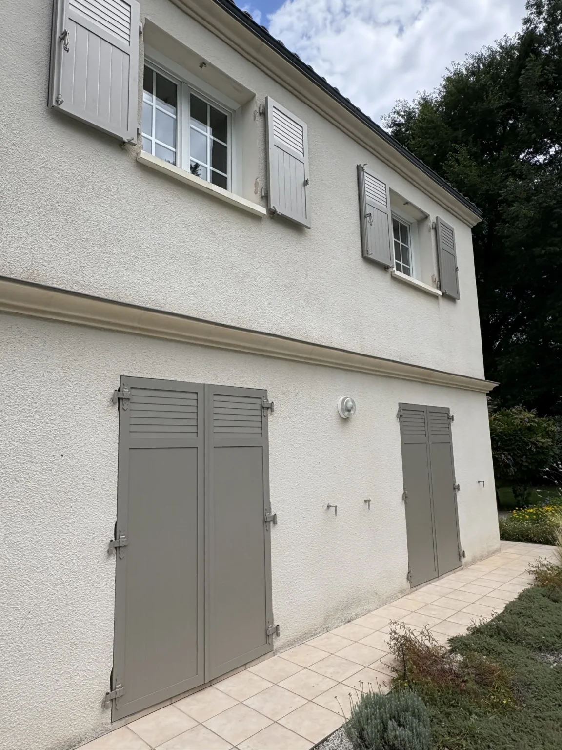 Deux fenêtres équipées de volets battants aluminium à double vantail, finition gris sable 2800