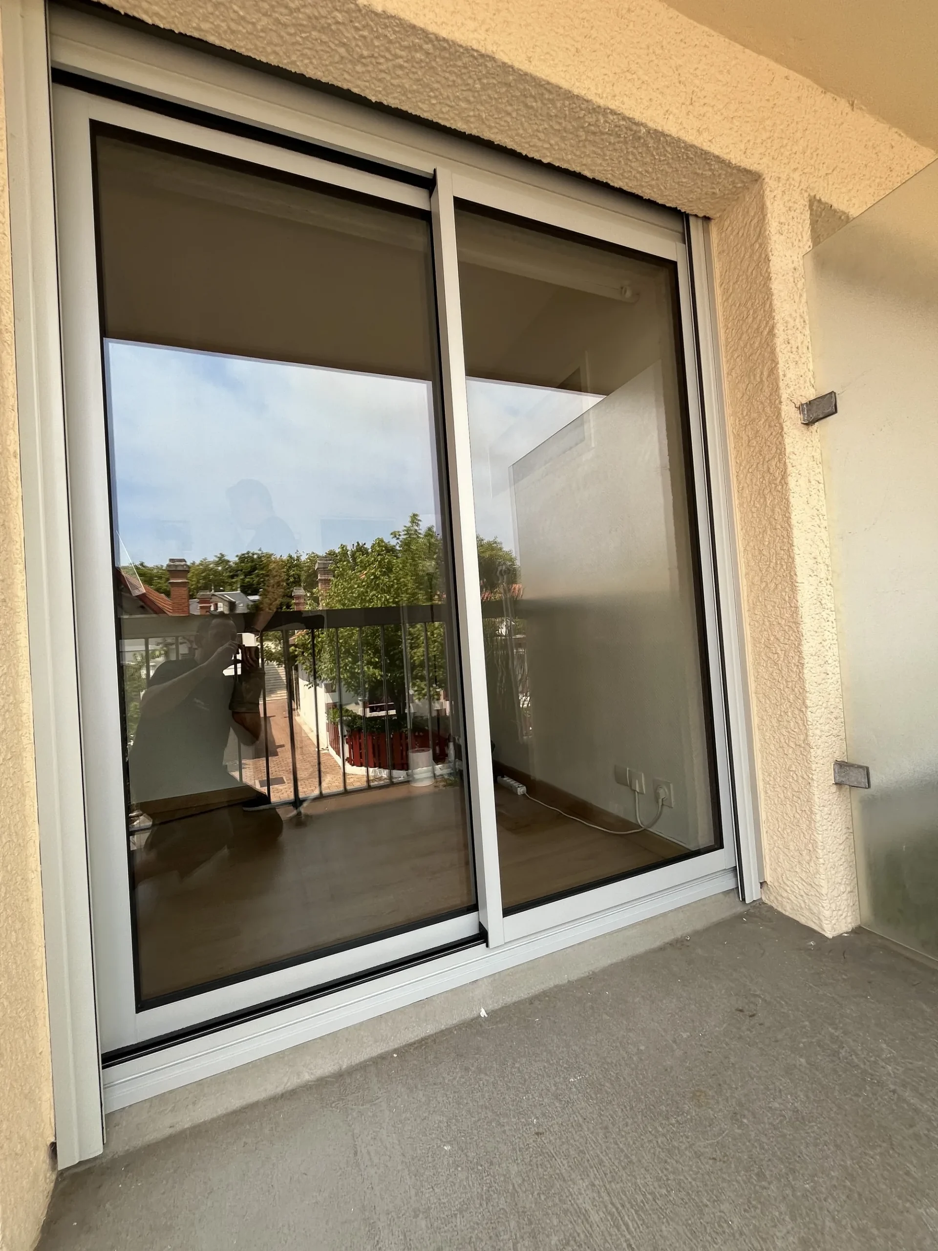 Loggia d'un appartement d'Arcachon avec coulissant aluminium et vue sur les toits de tuiles