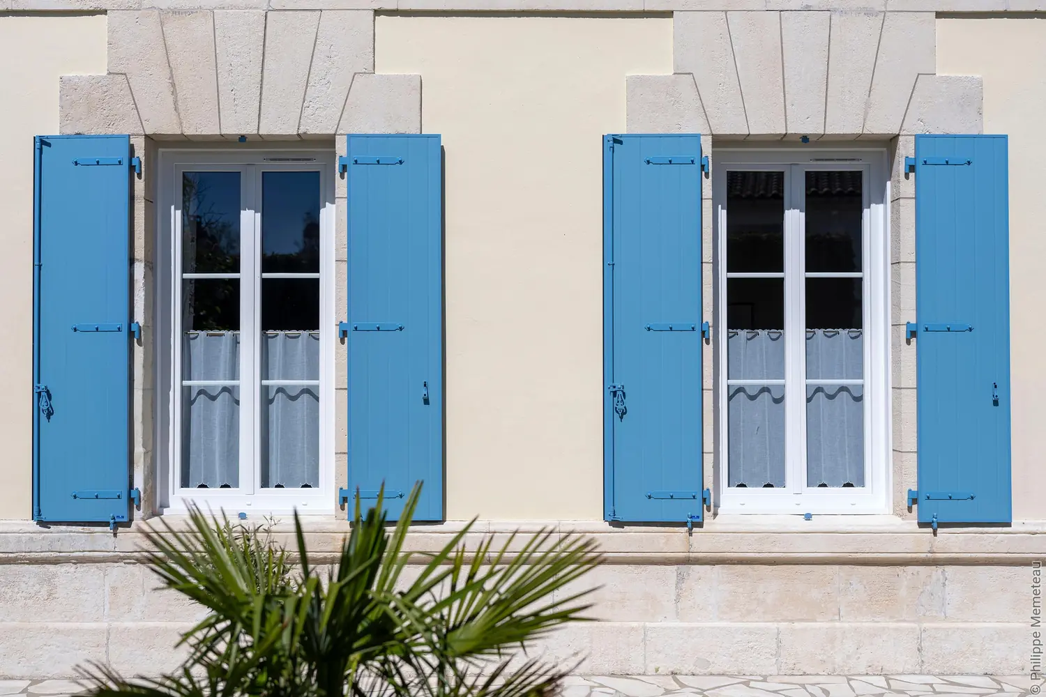 Fenêtres PVC blanches et volets battants bleus posés en rénovation sur une maison