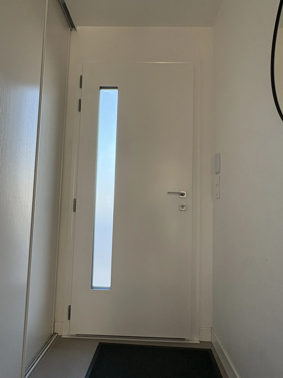 Entrée éclairée par le vitrage vertical de la porte, vue de trois quarts