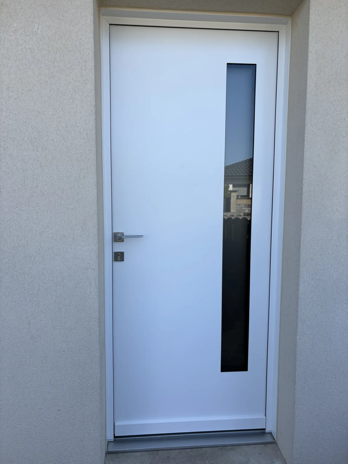 Porte d’entrée aluminium blanche à bandeau vitré vertical, vue de façade à Marcheprime