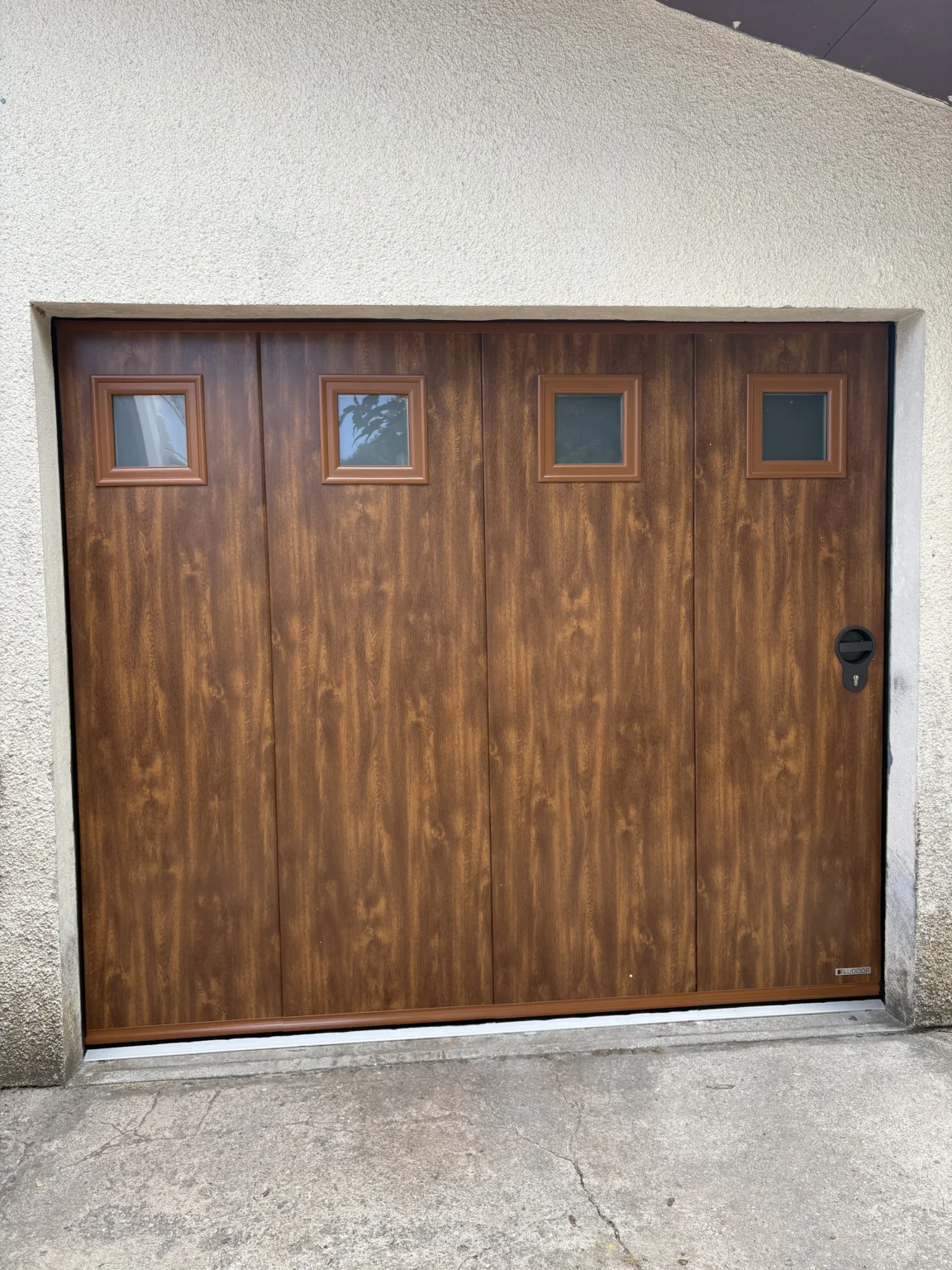 Porte de garage sectionnelle Aludoor avec portillon intégré et hublot, finition imitation bois, à Martignas-sur-Jalles