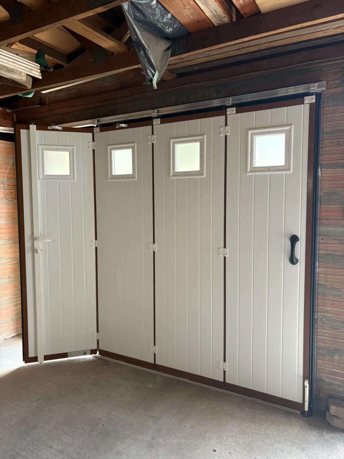 Portillon intégré ouvert dans une porte de garage sectionnelle à ouverture latérale, vue de l'intérieur du garage à Martignas-sur-Jalles