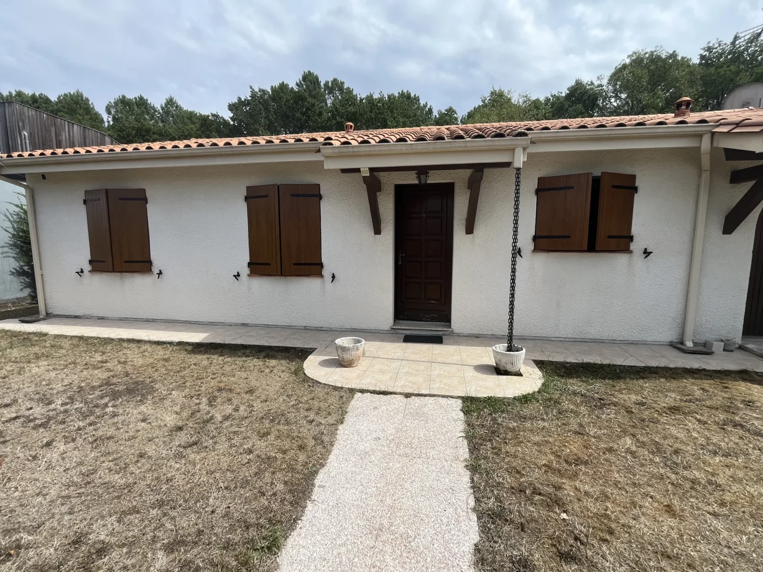 Façade de maison à Martignas-sur-Jalles avec porte d'entrée et volets battants assortis en chêne doré