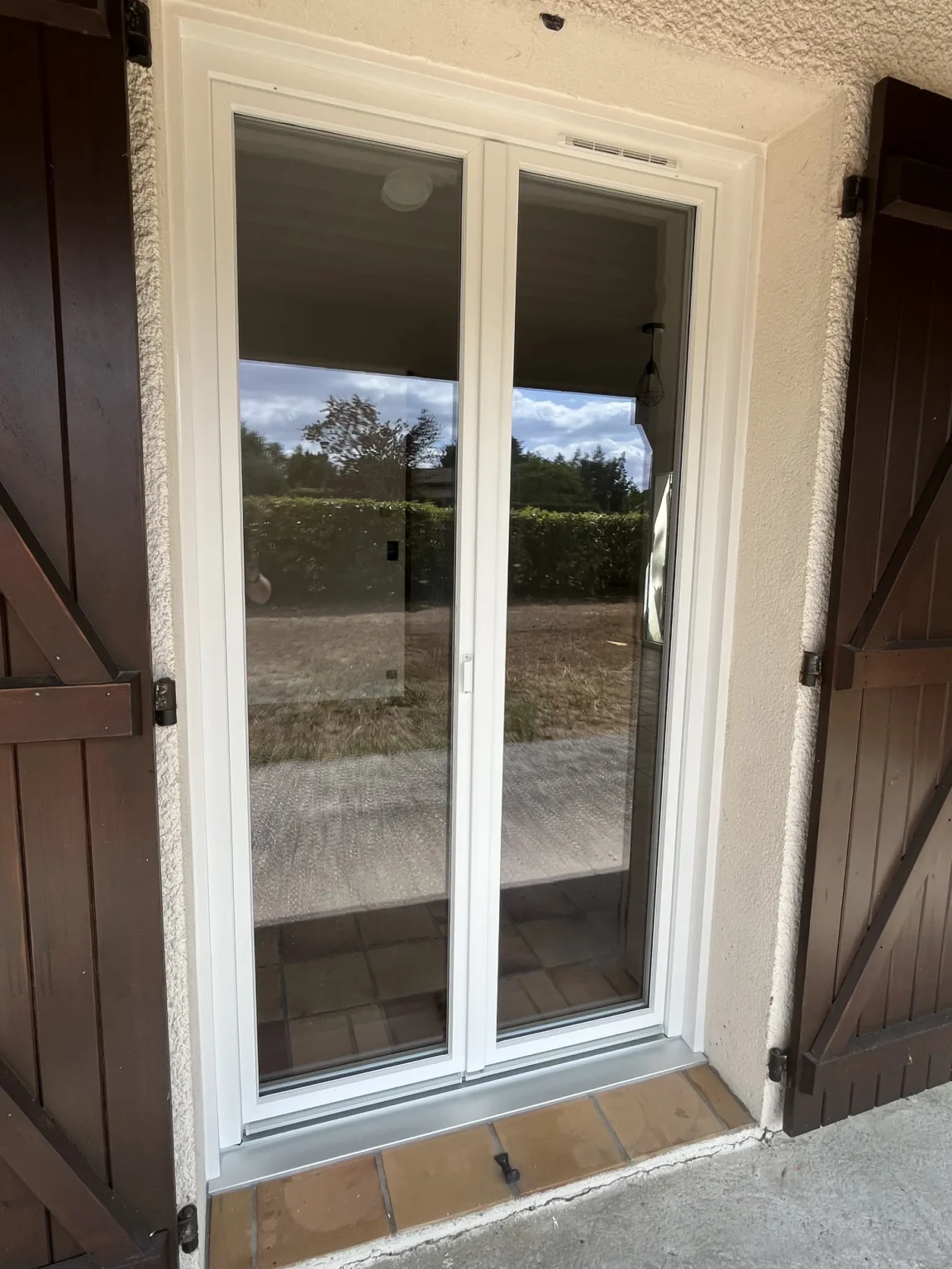Porte-fenêtre PVC blanche à Saint-Jean-d’Illac, volets battants bois d’origine ouverts de part et d’autre