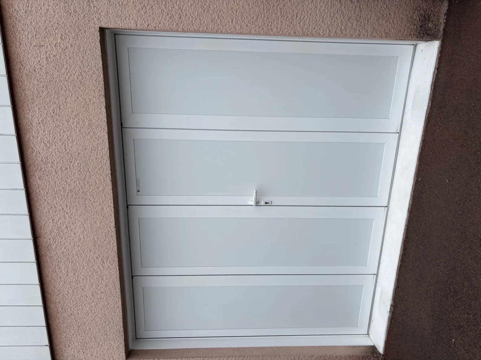 Vantaux à panneaux lisses et poignée à cylindre d'une porte de garage battante en aluminium
