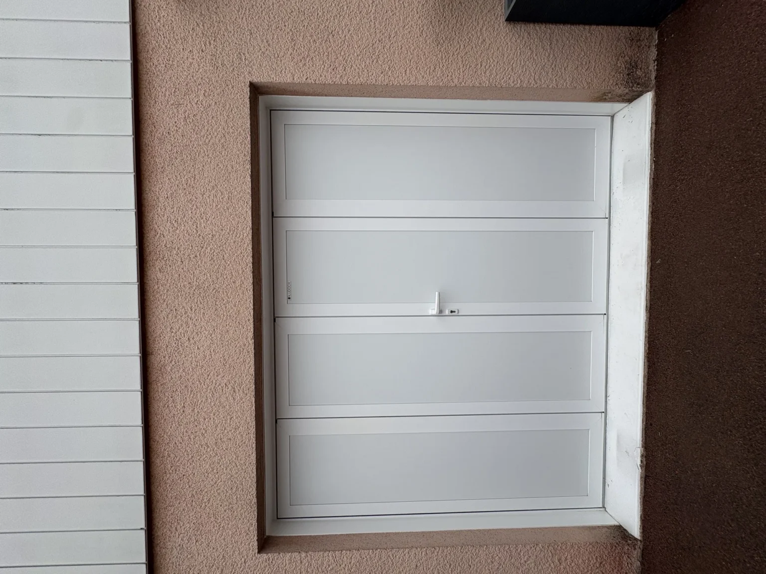 Seconde porte de garage battante avec son dormant blanc posé en tableau, au-dessus du seuil